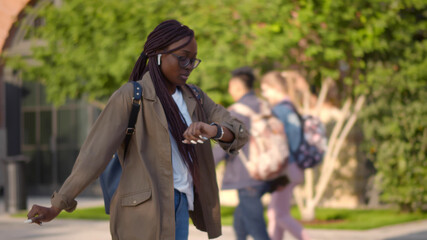Young african female student late for classes running on university campus