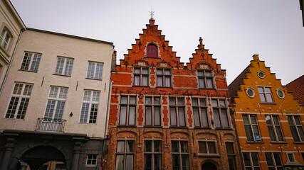 Fototapeta premium Bruges, Belgium - May 12, 2018: Roofs And Windows Of Old Authentic Brick Houses On Street Sint-Jakobsstraat