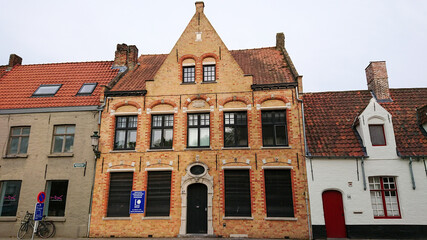 Fototapeta na wymiar Bruges, Belgium - May 12, 2018: Roofs And Windows Of Old Authentic Brick Houses On Street Vrijdagmarkt
