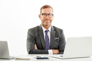 Studio portrait of a middle aged sales director businessman sitting at desk with folded arms and working. Isolated white background with copy space.
