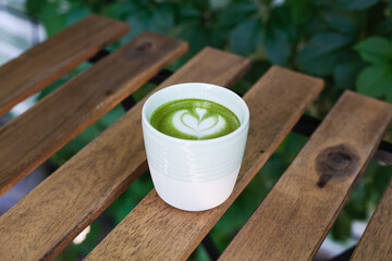 A cup of green tea matcha latte on wooden background at cafe. Healthy food concept. Place for text. Top view. Close-up.