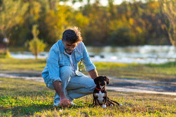 Mature man picking up dog poop from the lawn at the public park. 