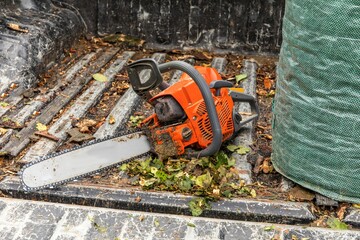 Chainsaw resting on a car. Lumberjack tools. Work in forest.