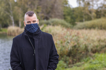 A man in a mask stands in the park