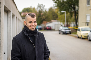 Fototapeta premium A man stands in front of garages and smiling in a small city in Hungary