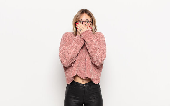 young pretty woman covering mouth with hands with a shocked, surprised expression, keeping a secret or saying oops