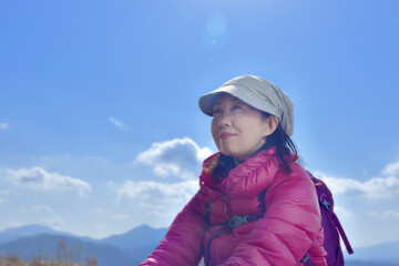 Fototapeta na wymiar 登山者が休息しているシルエットと太陽光が輝く青空
