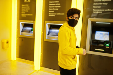 Urban young hipster indian man in a fashionable yellow sweatshirt at bank. Cool south asian guy...