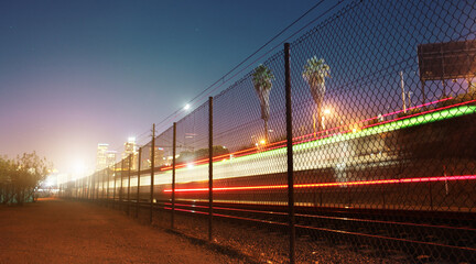 Long exposure shot of train moving towards downtown Los Angeles skyline at night. Copyspace.