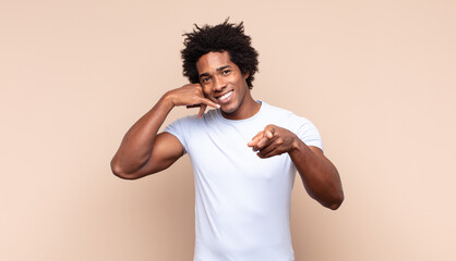 young black afro man feeling confused, clueless and unsure, weighting the good and bad in different...