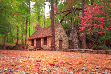 Old mill wheel attached to stone building in Georgia near the woods during autumn with fall foliage  © Lenspiration