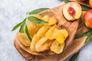Dried fruits or candied and Fresh peaches with leaves on stone background