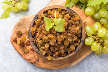 Golden raisins  in bowl on stone background, table top view. Dried fruit, healthy snack food