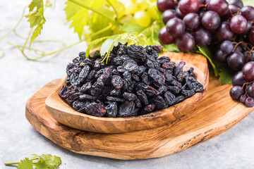 Black raisins  in bowl on stone  background, table top view. Dried fruit, healthy snack food