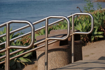 Three stainless steel handrails at stairs to an ocean beach