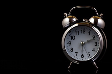 Nice old vintage chrome metal twin bell alarm clock on black background with copy space..