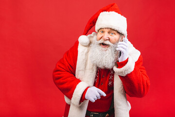 Portrait of nice attractive handsome amazed Santa using phone gadget 5g fast speed blog blogger browsing multimedia isolated over red background.