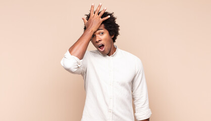 young black afro man raising palm to forehead thinking oops, after making a stupid mistake or...