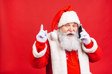 Portrait of nice attractive handsome amazed Santa using phone gadget 5g fast speed blog blogger browsing multimedia isolated over red background.