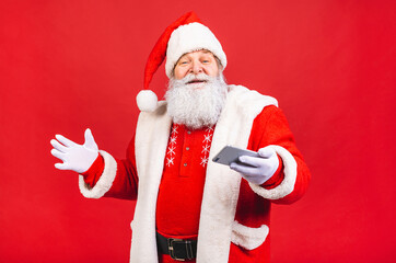 Santa Claus standing isolated on red background. Christmas and new year concept. Using tablet computer.