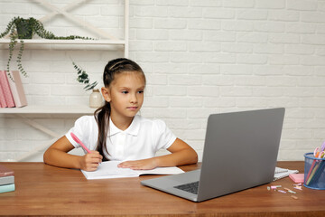happy little child girl using laptop computer, studying through online e-learning system.