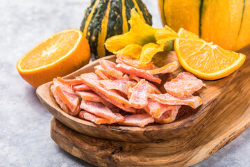 Dried pumpkin slices in plate on a dark stone background. Candied pumpkin.