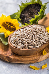Sunflower seeds in a small plate with sunflower plant. Healthy vegetarian protein nutritious food.