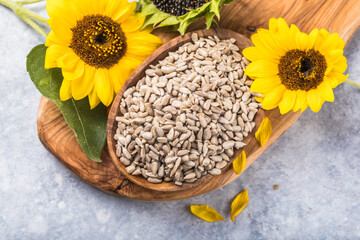 Obraz na płótnie Canvas Sunflower seeds in a small plate with sunflower plant. Healthy vegetarian protein nutritious food.