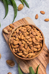 Peeled whole almonds in bowl with leaf