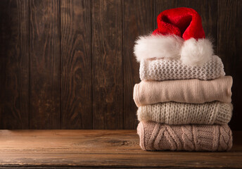 Obraz na płótnie Canvas Cozy winter knitted sweaters and red Santa hat on rustic wooden background.