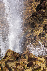 D&eacute;tail d'un geyser d'eau sortant d'un trou dans la caye sur le littoral avec la mer bleu intense 
