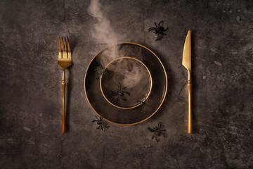 Vintage template with old metal plates, golden cutlery, spiders and smoke on black stone background for Halloween design. Halloween celebration concept. Flat lay style.