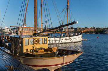 Obraz premium Sail boats at a quay an early sunny morning in autumn in Stockholm harbor at the island Skeppsholmen