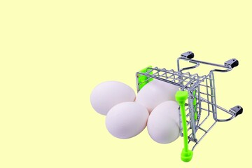 Close up view of shopping cart with white eggs on yellow background. Eastern. Food. Shopping.