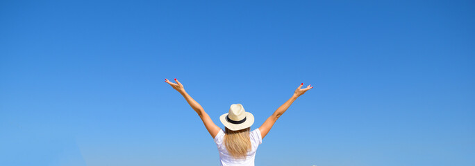 Naklejka premium Woman in hat raised her hands against the blue sky