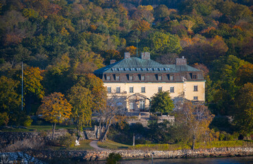Fototapeta na wymiar Old museum house on the ness Waldemarsudde embedded in color full autumn trees