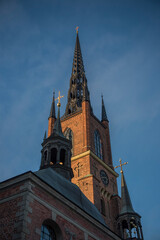 Fototapeta na wymiar Brick and steel tower on the church Riddarholmskyrkan on the island Riddarholmen in the old town Gamla Stan in Stockholm an early morning