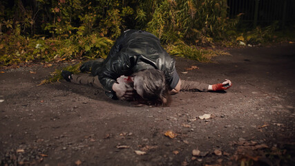 Zombie eating dead man lying on ground outdoors