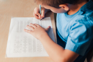 Close up of cute child doing his homework. Kid writing different lines by pencil. Children education concept.