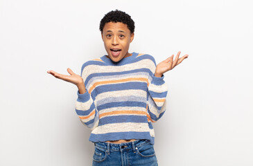 afro young black woman feeling happy, excited, surprised or shocked, smiling and astonished at...