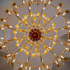 A chandelier from bottom view with colorful ceiling as background