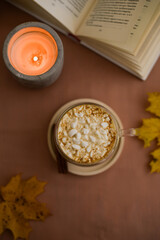 a cup of cocoa, books, autumn leaves and candle standing on grown table still life flat lay