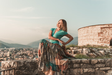 Fototapeta premium Adult woman does sports exercise. Yoga teacher doing an asana on the old city wall.