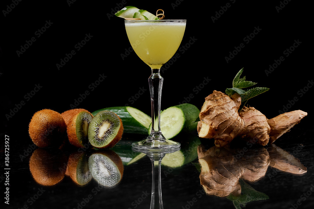 Wall mural cocktail of kiwi, ginger, cucumber on a black background on a mirrored table