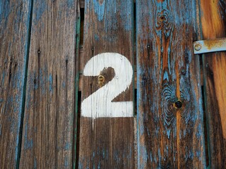 Number two on an old abandoned weathered blue colour wooden gate in Budapest suburb, Hungary