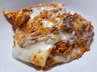 freshly baked lasagna piece on white plate close-up