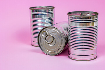 Tinned food and metal cans storage on light pink background.