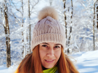 Redhaired girl in a knitted hat with bubo on a blurred background of a winter landscape