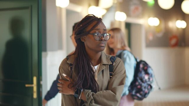 Depressed afro-american female student walking in college corridor