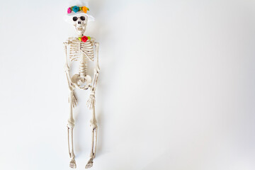 Skeleton with hat and colorful flowers on white background with copy space